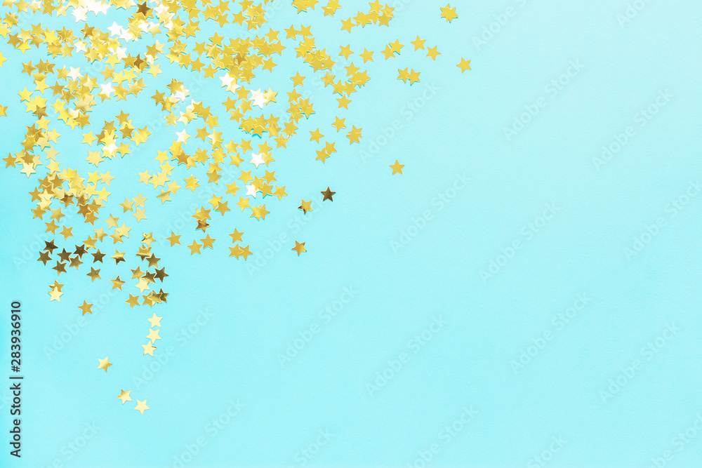 Holiday background with little golden stars on blue background. Flat lay, top view