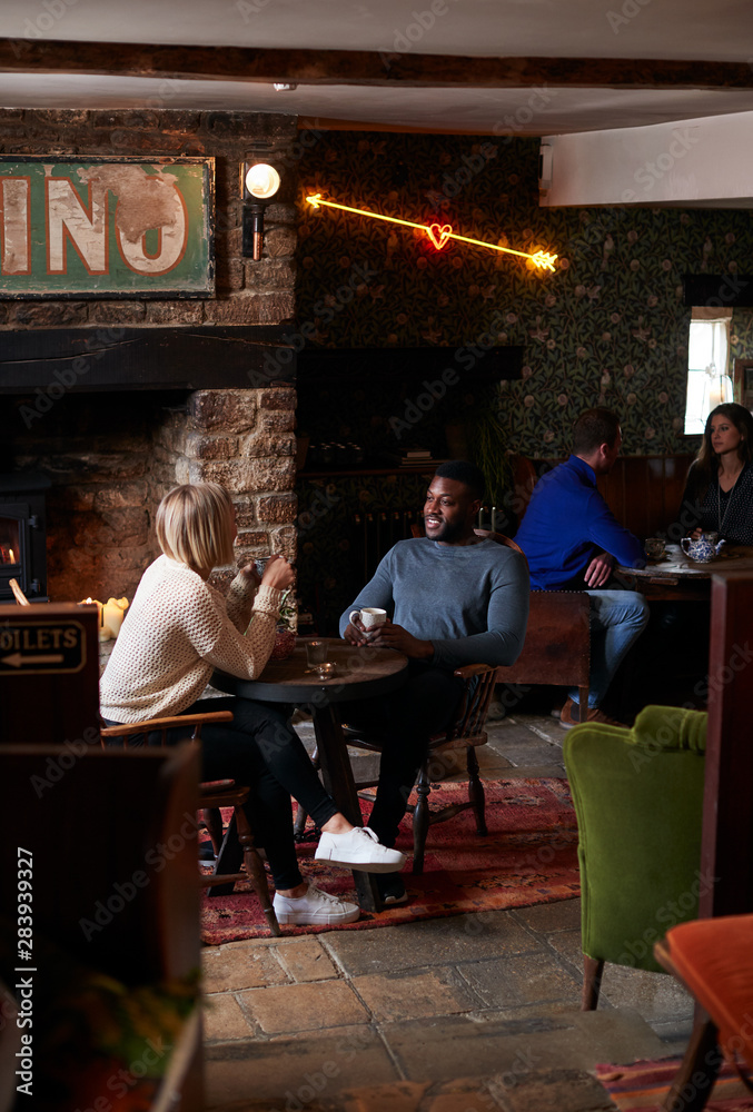Naklejka premium Couple Sitting At Table Drinking Tea In Traditional English Holiday Hotel