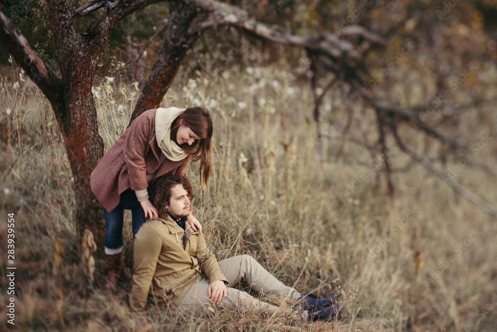 Young happy caucasian couple expecting a baby. Pregnant woman and her husband walking and having fun together outdoors in the autumn. Family, parenthood, love, happiness concept.