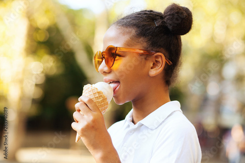 Obraz na plátně Cute girl in bright sunglasses eating ice-cream
