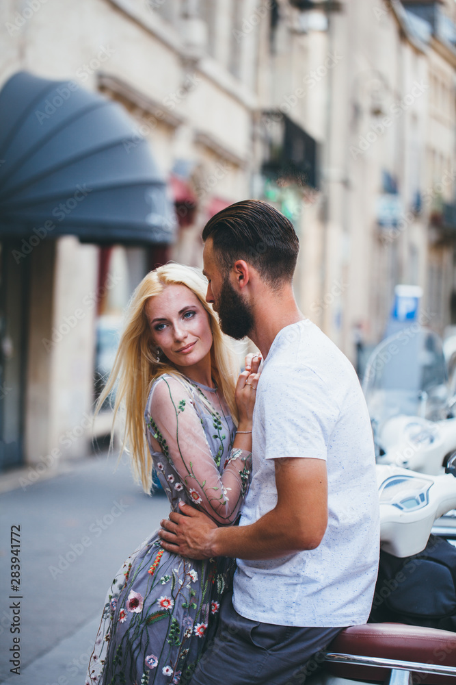 Blonde girl and Hipster handsome man with beard hugging and kissing on the city streets Blonde girl and Hipster handsome man with beard hugging and kissing on the city streets