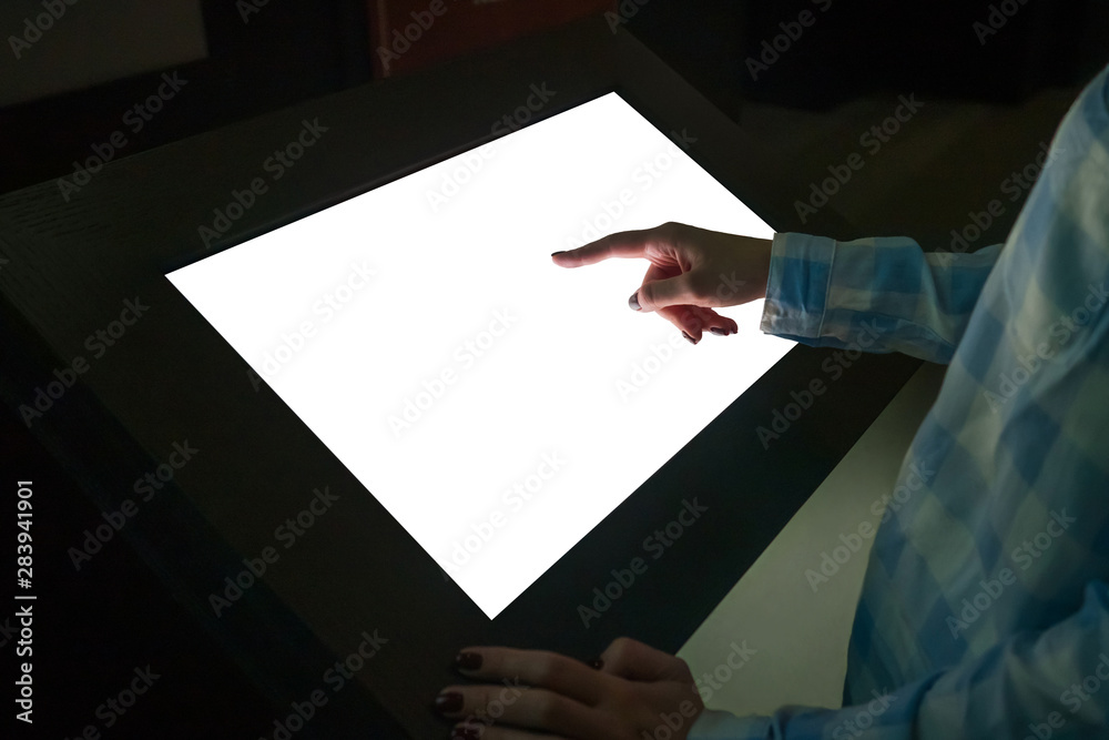 © zyabich - Mockup image - woman hand touching white empty interactive touchscreen display kiosk in dark room of modern technology museum. Mock up, template, scifi, education, futuristic and technology concept © zyabich - Mockup image - woman hand touching white empty interactive touchscreen display kiosk in dark room of modern technology museum. Mock up, template, scifi, education, futuristic and technology concept