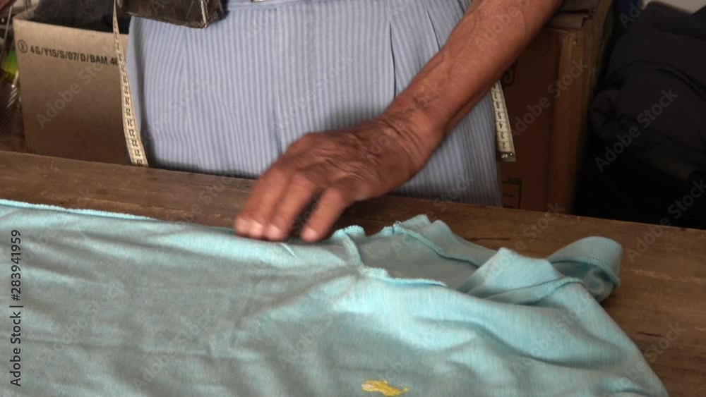Yesiluzumlu village, Mugla, Turkey - 71th of July 2019: 4K Hands of an old tailor remodeling a T-shirt