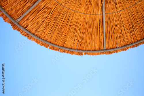 Summer background with blue sky and sun umbrella