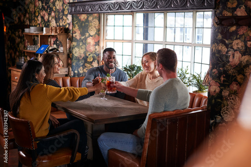 Group Of Friends Making Toast As They Meet For Lunchtime Drinks In Traditional English Pub