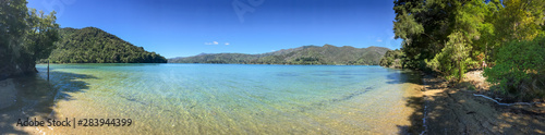 A shoreline level sweeping panoramic view of the beautiful Marlbough Sounds, New Zealand, sparkling waters, clear blue skies