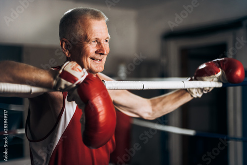 Happy funny senior boxer man with red gloves in the ring © Petryshak