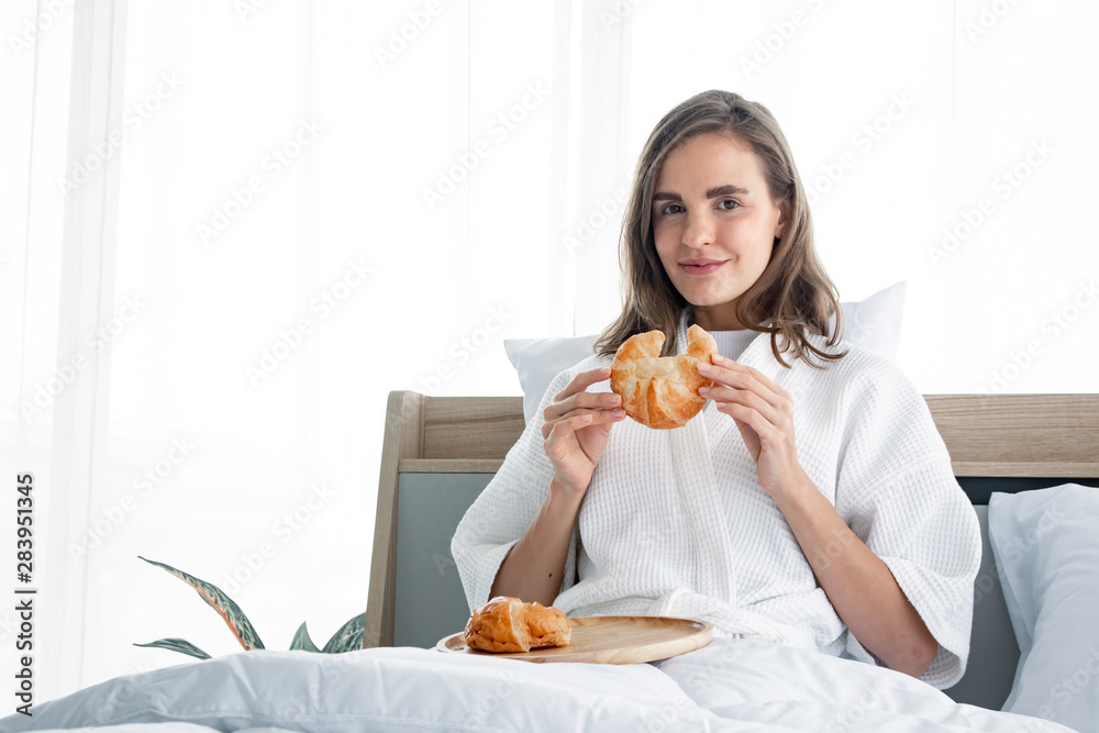 Young woman caucasian in pajama eat bread after I woke up the morning.