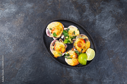 Baked seafood shellfish scallops with cheese and lemon. black background