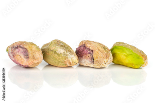 Group of four whole ripe green pistachio in closeup in row isolated on white background