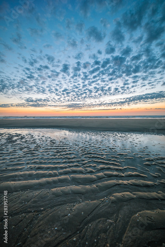 Ripples in the sand of the beach during a colorul sunset at the dutch coast