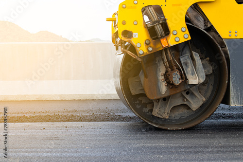 Asphalt road surface is smoothed with steel wheels, road construction machinery, asphalt paver © Nui