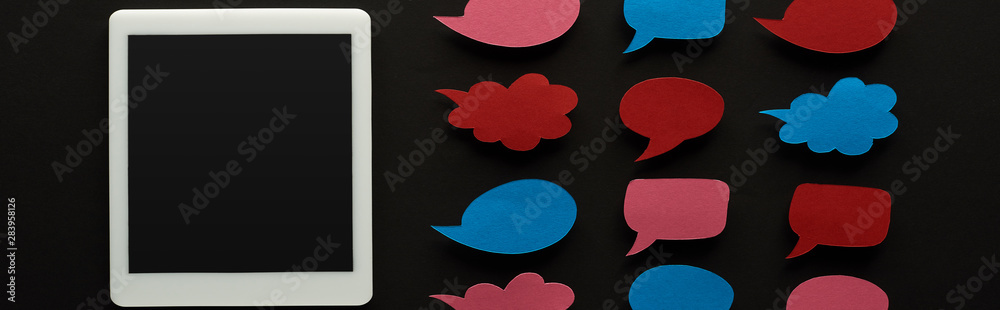 panoramic shot of digital tablet with blank screen on black background near empty speech bubbles, cyberbullying concept panoramic shot of digital tablet with blank screen on black background near empty speech bubbles, cyberbullying concept