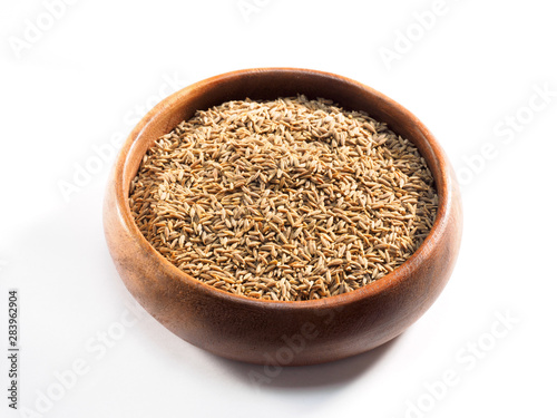 Cumin seeds (Cuminum), jeera in a wooden cup on a white background