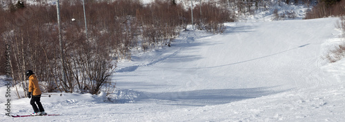 Skier downhill on snowy ski slope at sun winter day