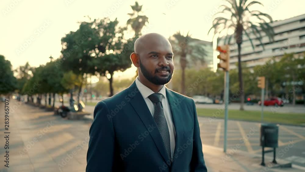 Indian businessman wearing blue suit standing near office or hotel. Travel business concept. Waiting for taxi or driver