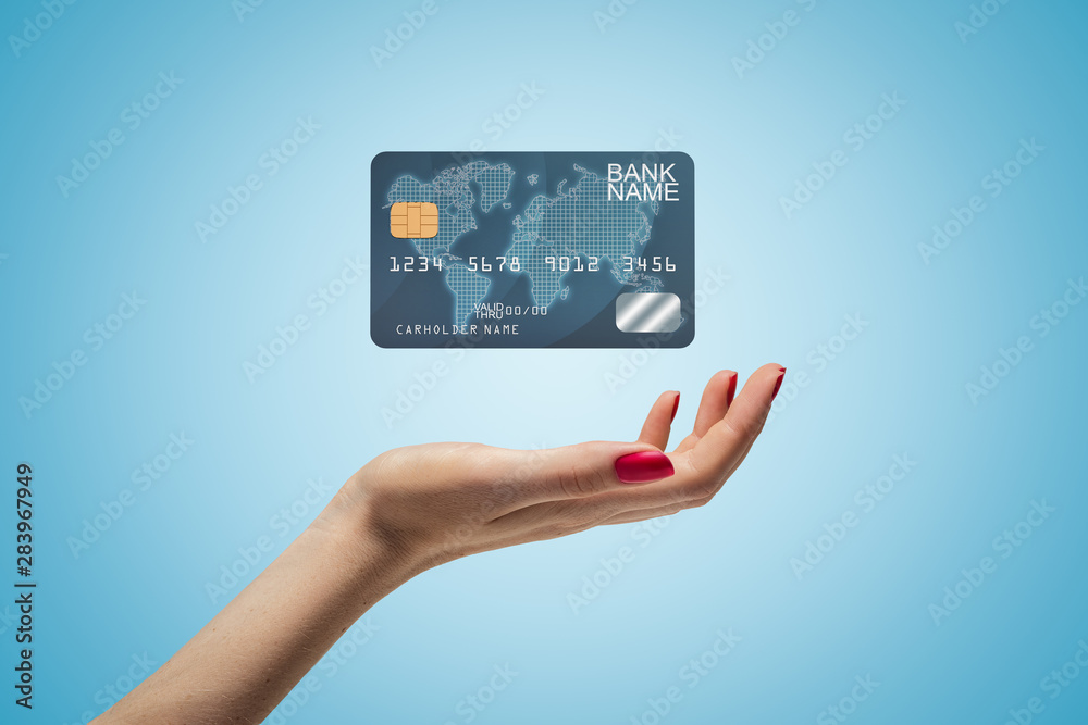 Side closeup of woman's hand facing up and levitating plastic bank card on light blue gradient background. Side closeup of woman's hand facing up and levitating plastic bank card on light blue gradient background.
