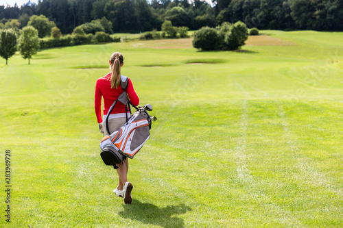Rear view of woman carrying golf bag