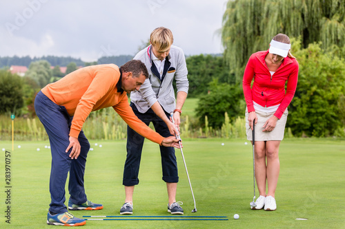 Male trainer teaching the couple to play golf