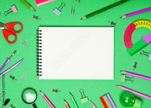 School accessories and office stationery and emty notrbook on green background. photo