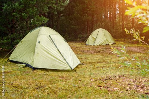 Camping tent with blured image group of backpackers relaxing near campfire, tourist background.