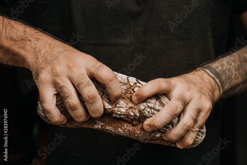 Male hands breaking freshly baked bread, closeup © Daria