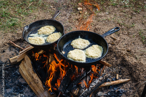 Potato pancakes fried in hot oil on a nature background. Preparing food on campfire in wild camping. Ukrainian cuisine