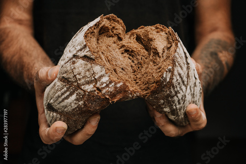 Male hands breaking freshly baked bread, closeup