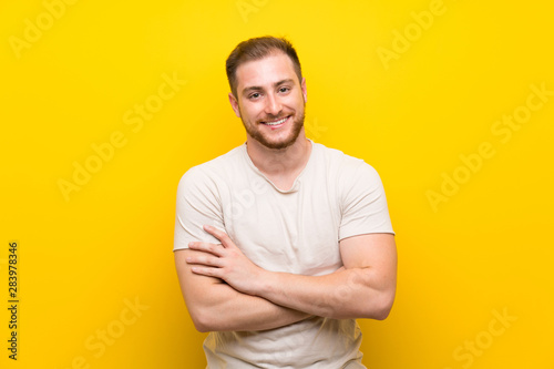 Handsome man over yellow background laughing
