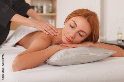 Charming woman enjoying relaing massage by professional masseuse. Recreation, pampering concept