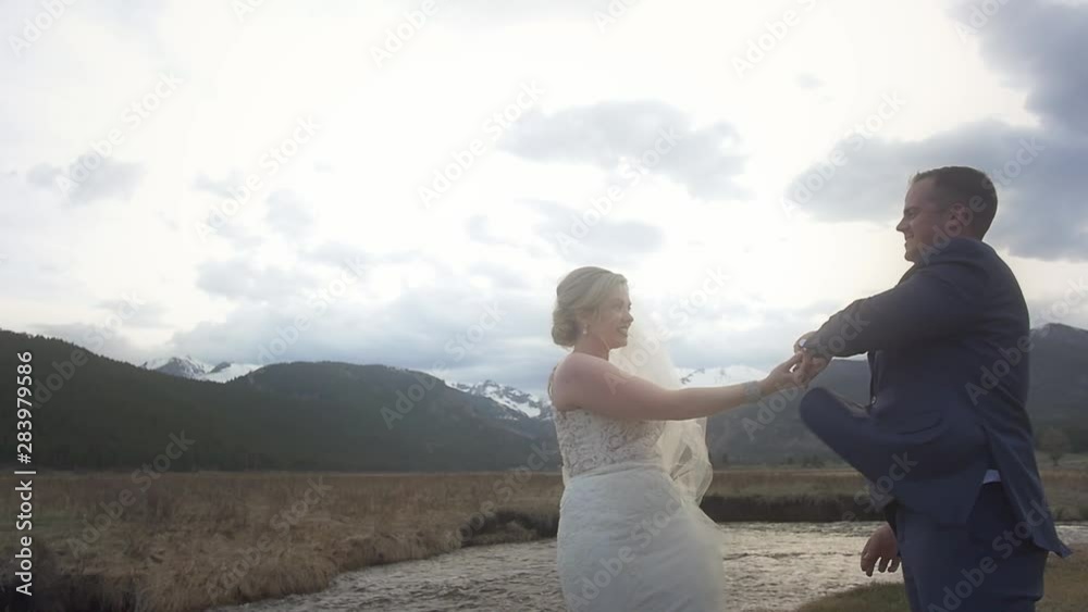 A bride and groom dance and twirl in a mountain field for their first dance for their outdoor elopement A bride and groom dance and twirl in a mountain field for their first dance for their outdoor elopement