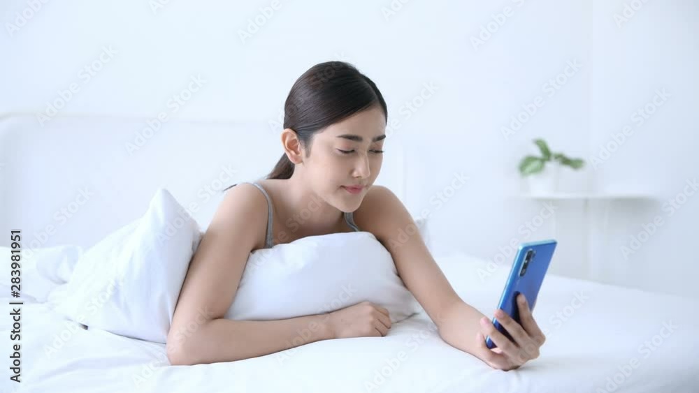Holiday concept. Asian girls are playing mobile phones in the bedroom. Holiday concept. Asian girls are playing mobile phones in the bedroom.