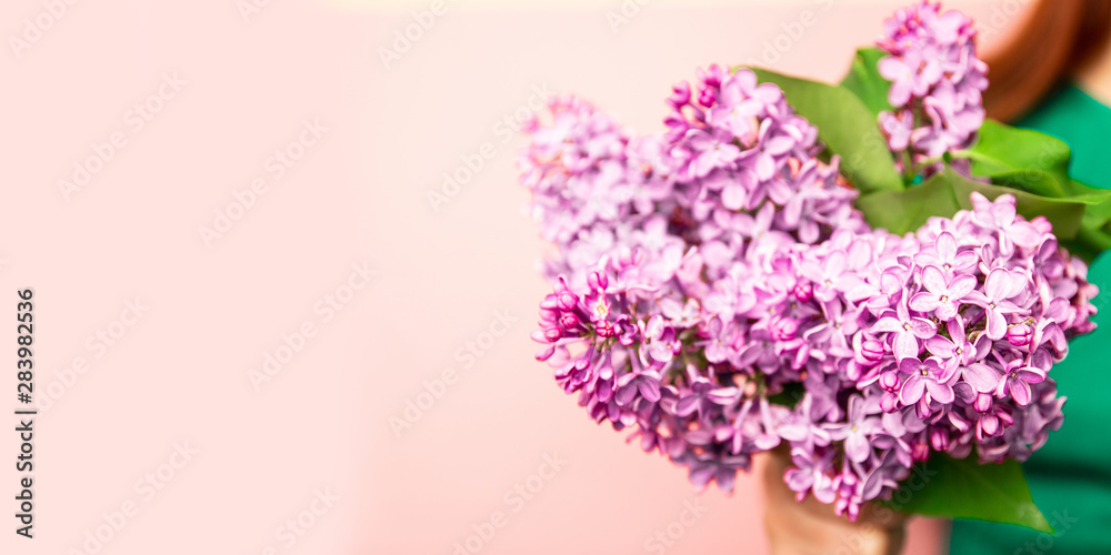 Portrait of a beautiful girl with blue eyes and a bouquet of lilacs on a pink background