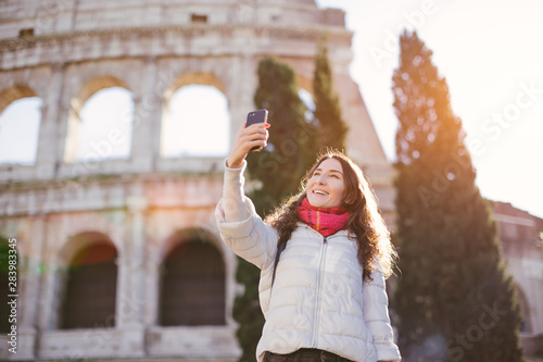 Photography Young beautiful smiling woman posing against Roman colosseum and making selfie w
