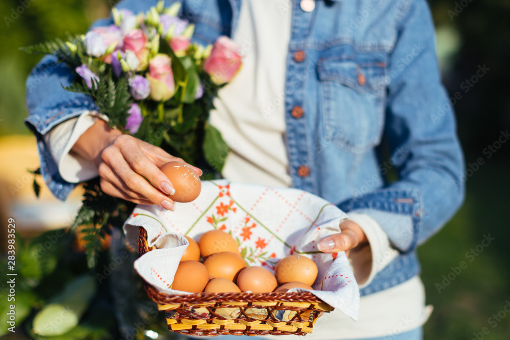 Female hands holding a basket with fresh eggs - countryside healthy lifestyle and ecology concept