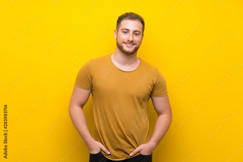 Blonde man over isolated yellow wall laughing Blonde man over isolated yellow wall laughing