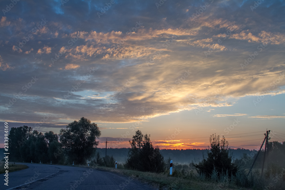 Landscape with an old patched asphalt road among fields and meadows at sunrise, selective focus Landscape with an old patched asphalt road among fields and meadows at sunrise, selective focus
