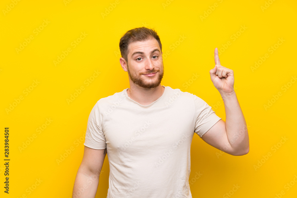 Handsome man over yellow background pointing with the index finger a great idea Handsome man over yellow background pointing with the index finger a great idea