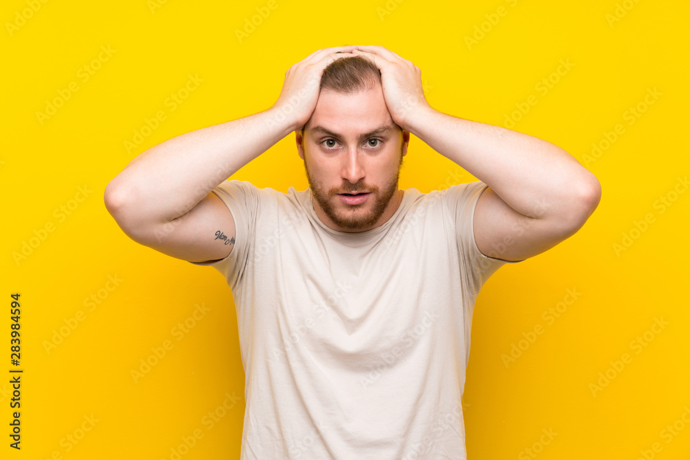 Handsome man over yellow background with surprise facial expression Handsome man over yellow background with surprise facial expression