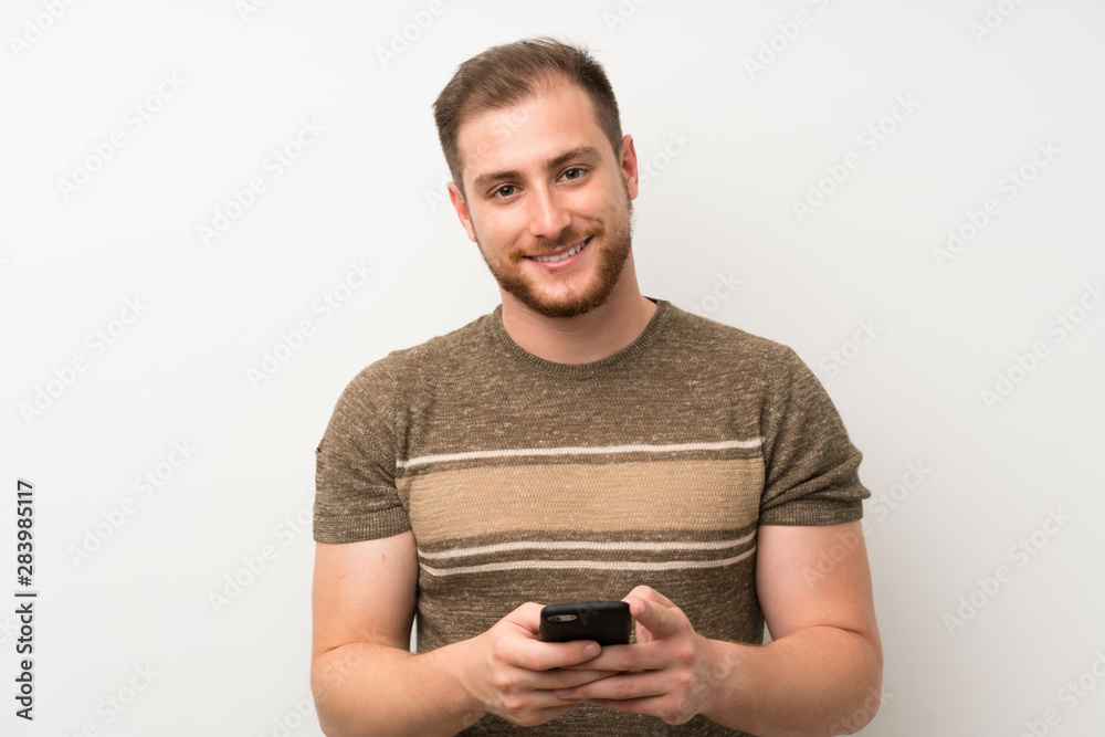 Handsome man over isolated white wall using mobile phone Handsome man over isolated white wall using mobile phone