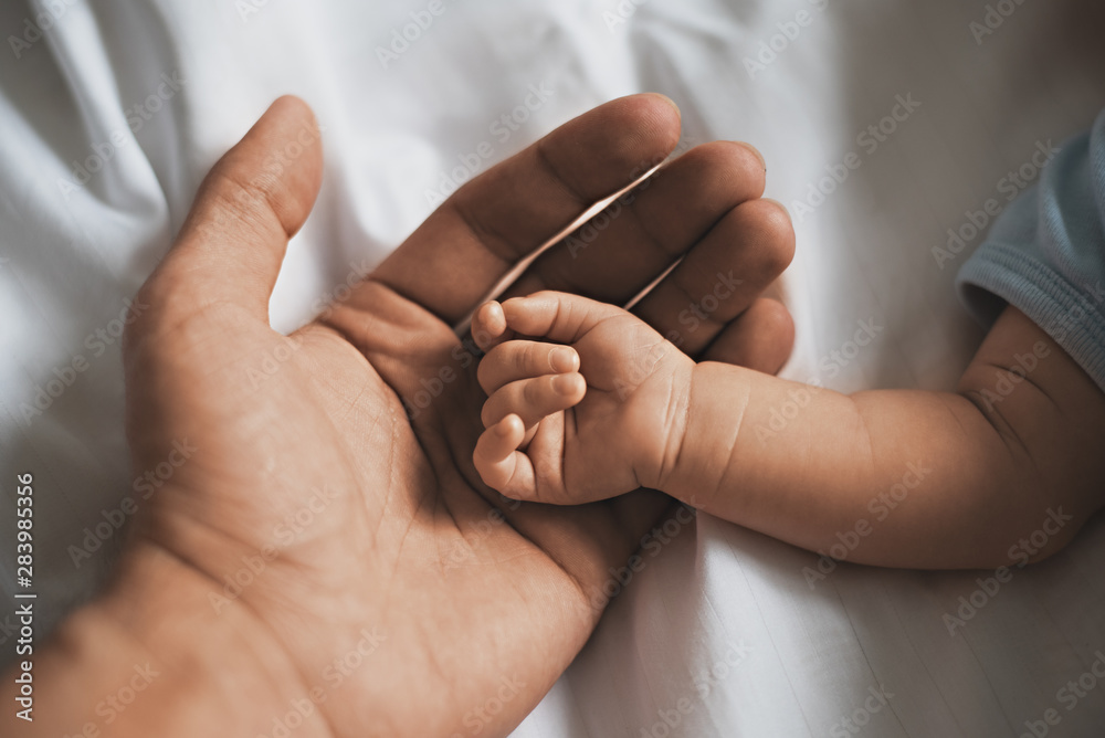 Close-up small hands of baby is lying in men of his father hands
