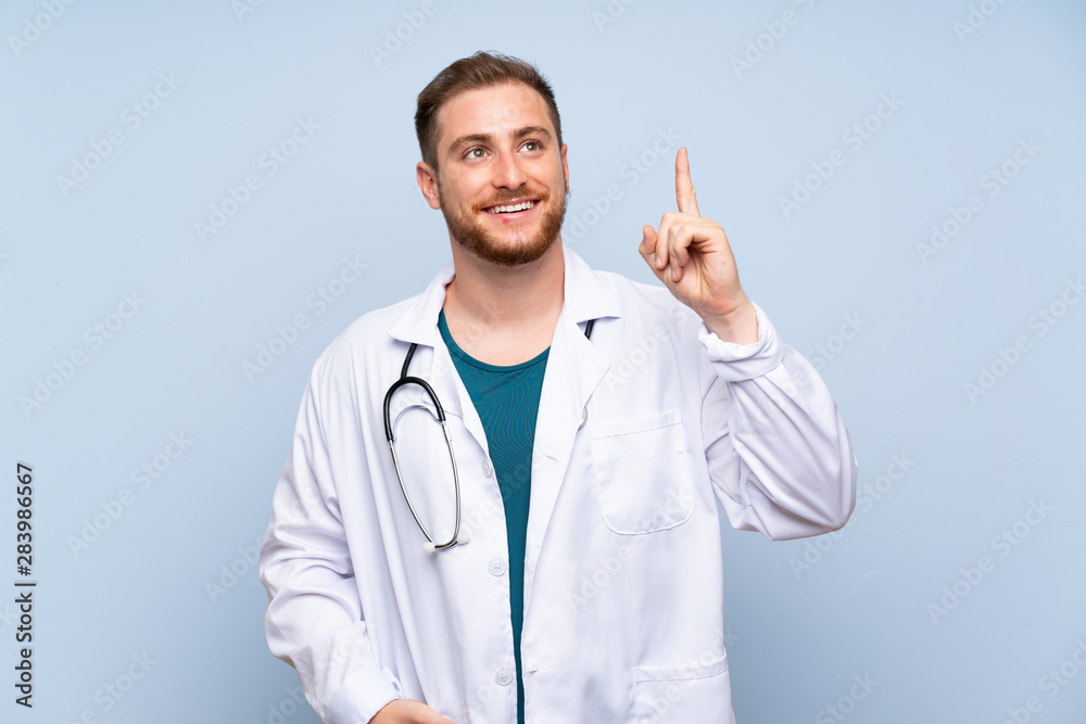 Handsome doctor man over blue wall intending to realizes the solution while lifting a finger up Handsome doctor man over blue wall intending to realizes the solution while lifting a finger up