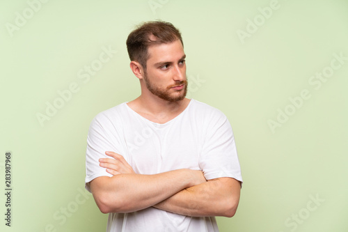 Handsome man over green background thinking an idea