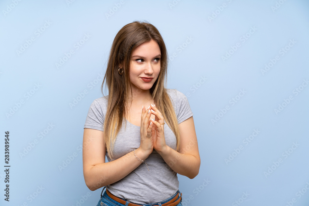 Teenager girl over isolated blue wall scheming something
