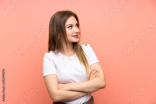 Teenager girl over isolated pink wall looking to the side