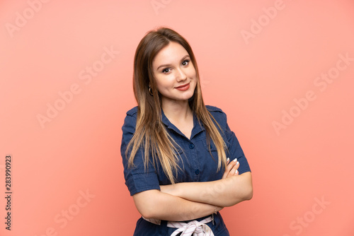 Teenager girl over isolated pink background keeping the arms crossed in frontal position
