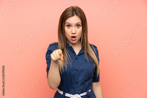 Teenager girl over isolated pink background surprised and pointing front