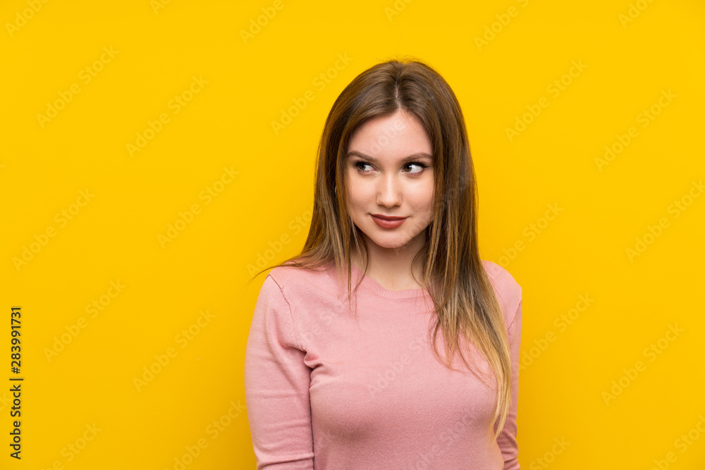 Obraz premium Teenager girl over isolated yellow background standing and looking to the side