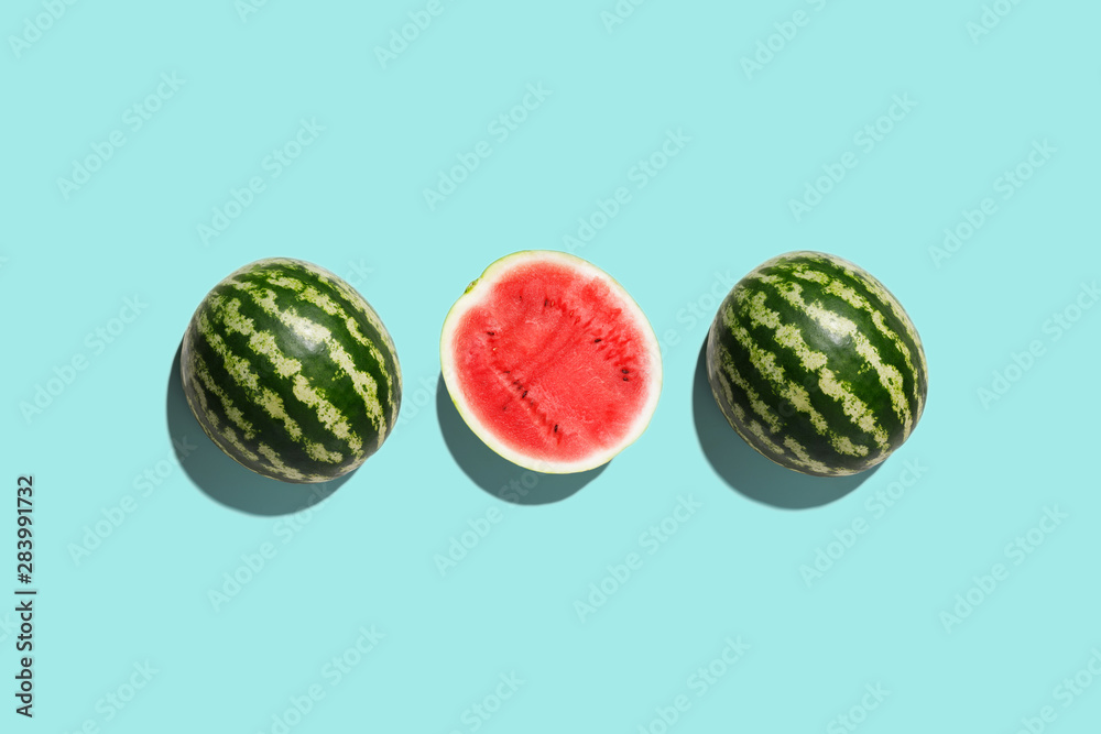 Three halves of watermelon in a row isolated on blue background Three halves of watermelon in a row isolated on blue background