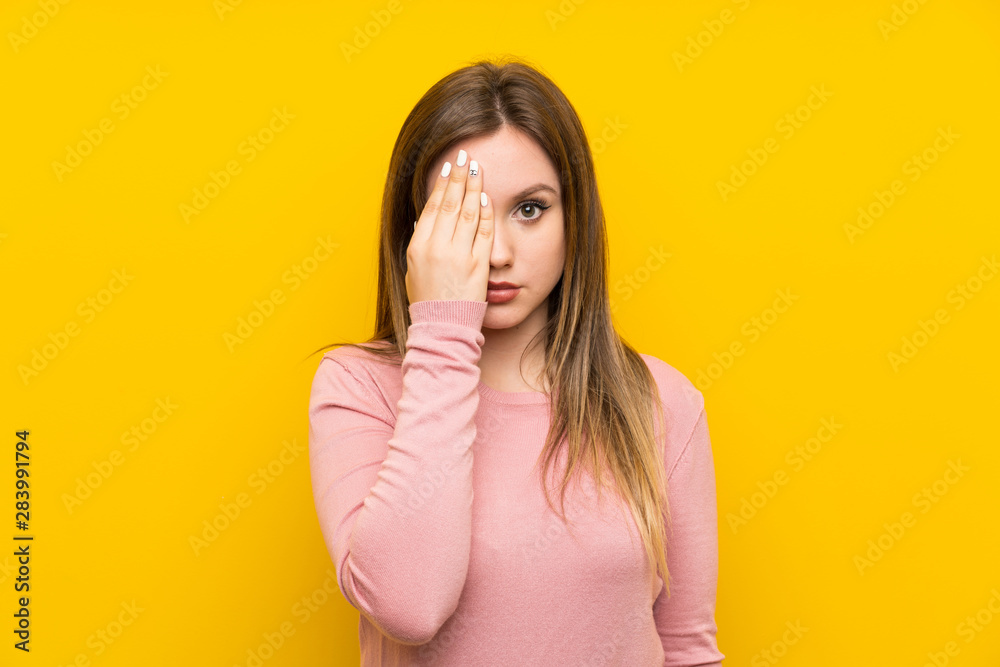 Teenager girl over isolated yellow background covering a eye by hand Teenager girl over isolated yellow background covering a eye by hand